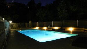 Una piscina con solárium de baldosas y una valla.