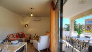 Un espace de vie compact comprenant un canapé, une table à manger et des chaises, un ventilateur de plafond et une vue sur l’extérieur.