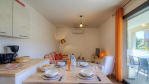 Un coin repas avec une table dressée pour quatre personnes, une machine à café et un canapé en arrière-plan.
