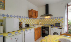 Eine kompakte Küche mit Kühlschrank, Herd, Mikrowelle und Waschmaschine.