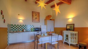 Une cuisine avec un crédence à carreaux, un four à micro-ondes, un réfrigérateur et une table à manger avec des chaises.