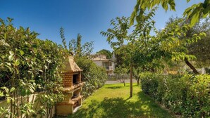 A brick outdoor oven in a garden with a house in the background. - Studio Molini - ALBITRECCIA (ALBITRECCIA)