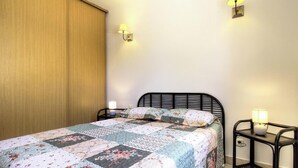 A bedroom with a bed, two bedside lamps, a wooden wardrobe, and a wall-mounted light fixture. - Santa Maria - PIETRALBA (PIETRALBA)