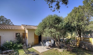 A house with a tiled roof, a patio with outdoor furniture, and a tree in the yard. - 15238 - SOTTA - Gîte (SOTTA)