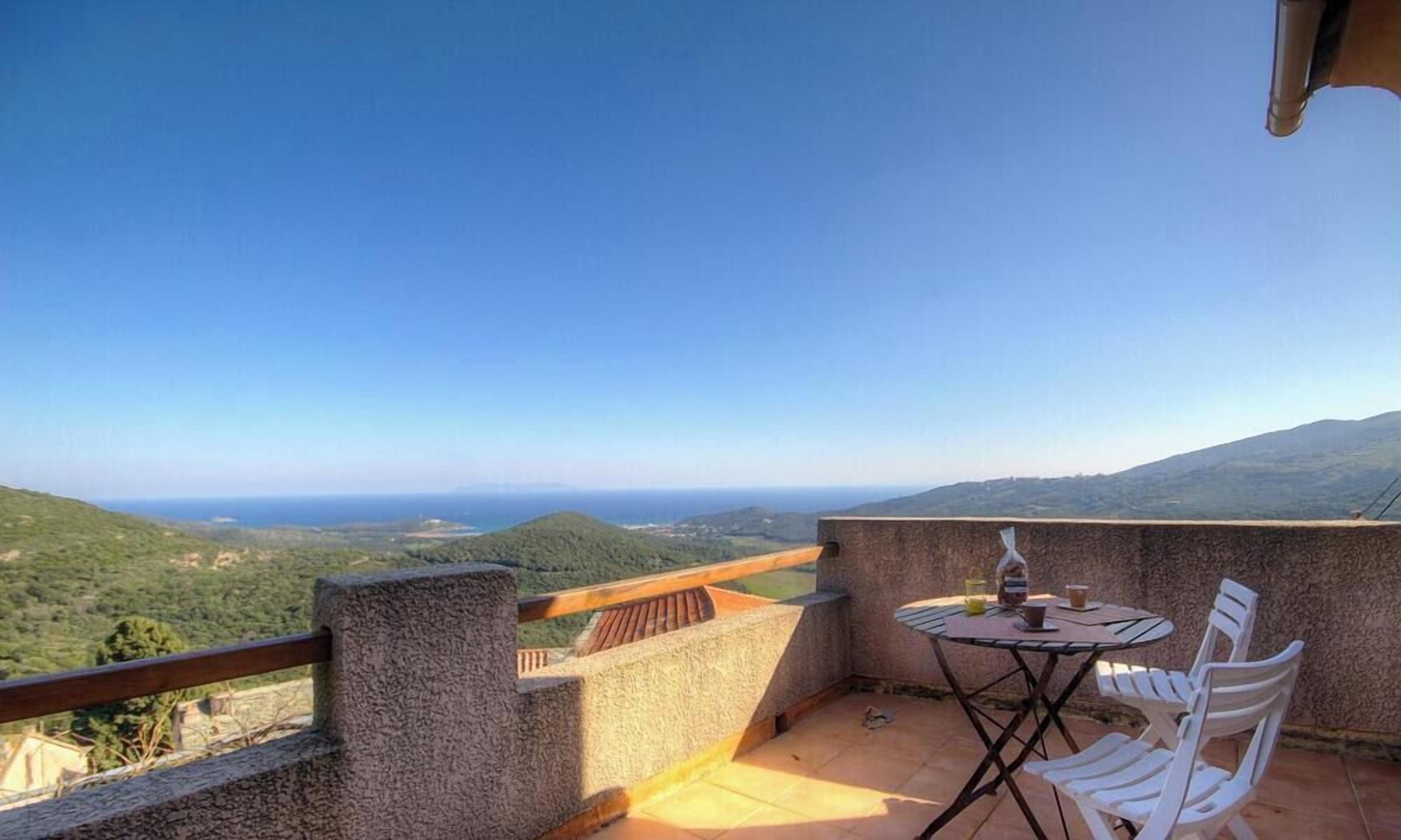 Un balcón con mesa y sillas, con vistas a un paisaje montañoso.