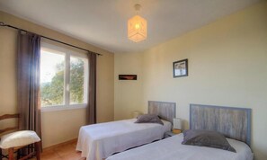 A room with two beds, a chair, a window with curtains, a hanging light fixture, and a framed picture on the wall. - A Gavera - ROGLIANO - Guest house (ROGLIANO)