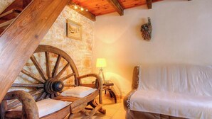 Una stanza rustica con un letto di legno, un muro in pietra e una grande struttura circolare in legno.