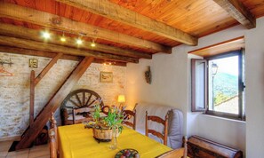 A rustic dining area with a wooden ceiling, a table set with a yellow tablecloth, a wicker basket with flowers, and a view of the countryside through a window. - I Pagliaghji - BISINCHI (BISINCHI)