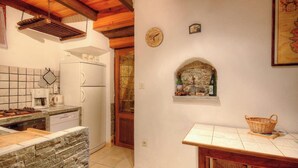 Una cucina con fornello, frigorifero e un piano di lavoro in pietra.