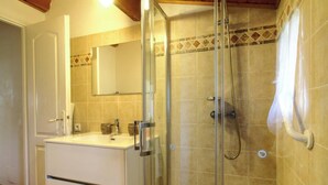 A bathroom with a glass-enclosed shower, a sink with a mirror above it, and a tiled wall. - A Casa Vecchia - LUCCIANA (LUCCIANA)