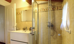 A bathroom with a glass-enclosed shower, a sink with a mirror above it, and a tiled wall. - A Casa Vecchia - LUCCIANA (LUCCIANA)