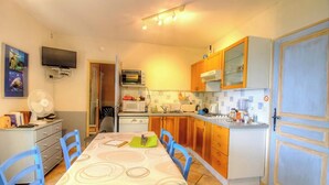 Une cuisine compacte comprenant une table à manger, des chaises, un four à micro-ondes, un four et un téléviseur fixé au mur.