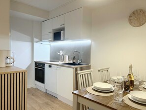 A modern kitchen with white cabinetry, a built-in oven, a dishwasher, and a stainless steel sink.