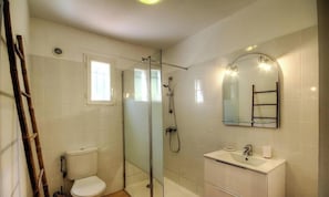 Ein Badezimmer mit einer Duschkabine, einer Toilette, einem Waschbecken und einem Spiegel.