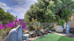 Un jardín con una estatua, rocas y una valla.