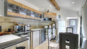 Una cocina compacta con electrodomésticos modernos, armarios de madera y una zona de comedor con una silla.