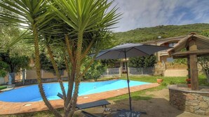 Una piscina con sillones de descanso y una pérgola.
