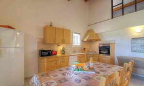 Cocina compacta con armarios de madera, microondas, cafetera y una mesa lista para comer.