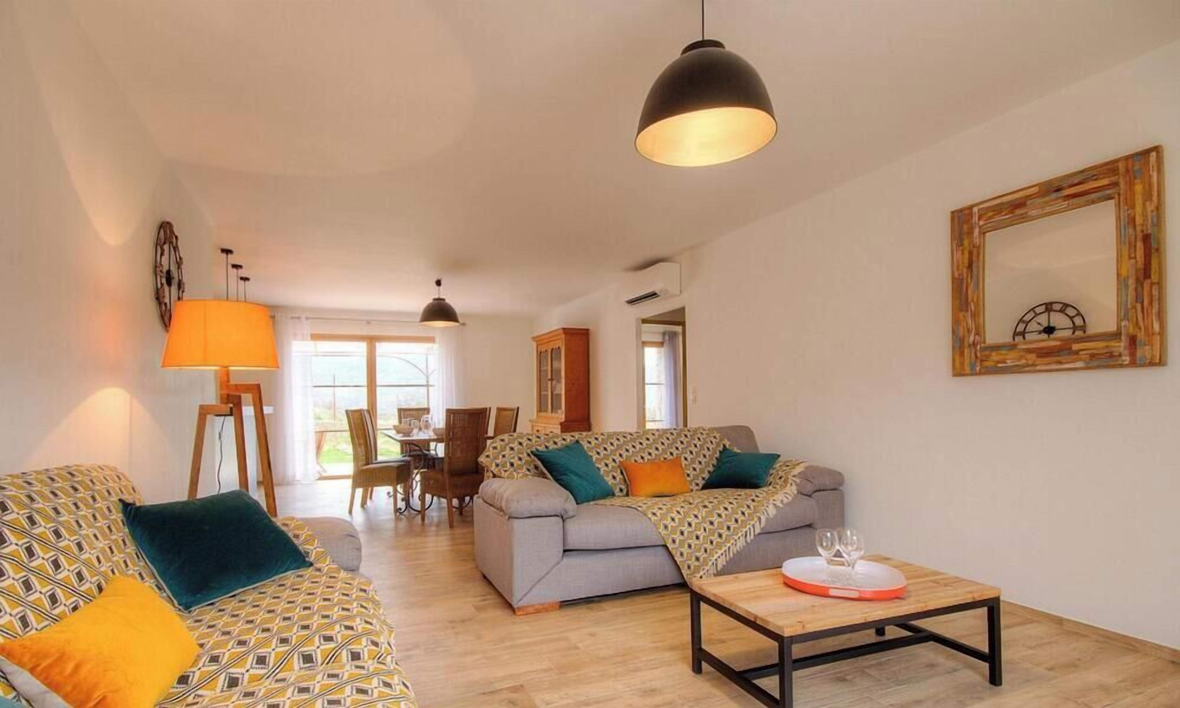 A living room with a sofa, a coffee table, and a dining area with chairs and a table.