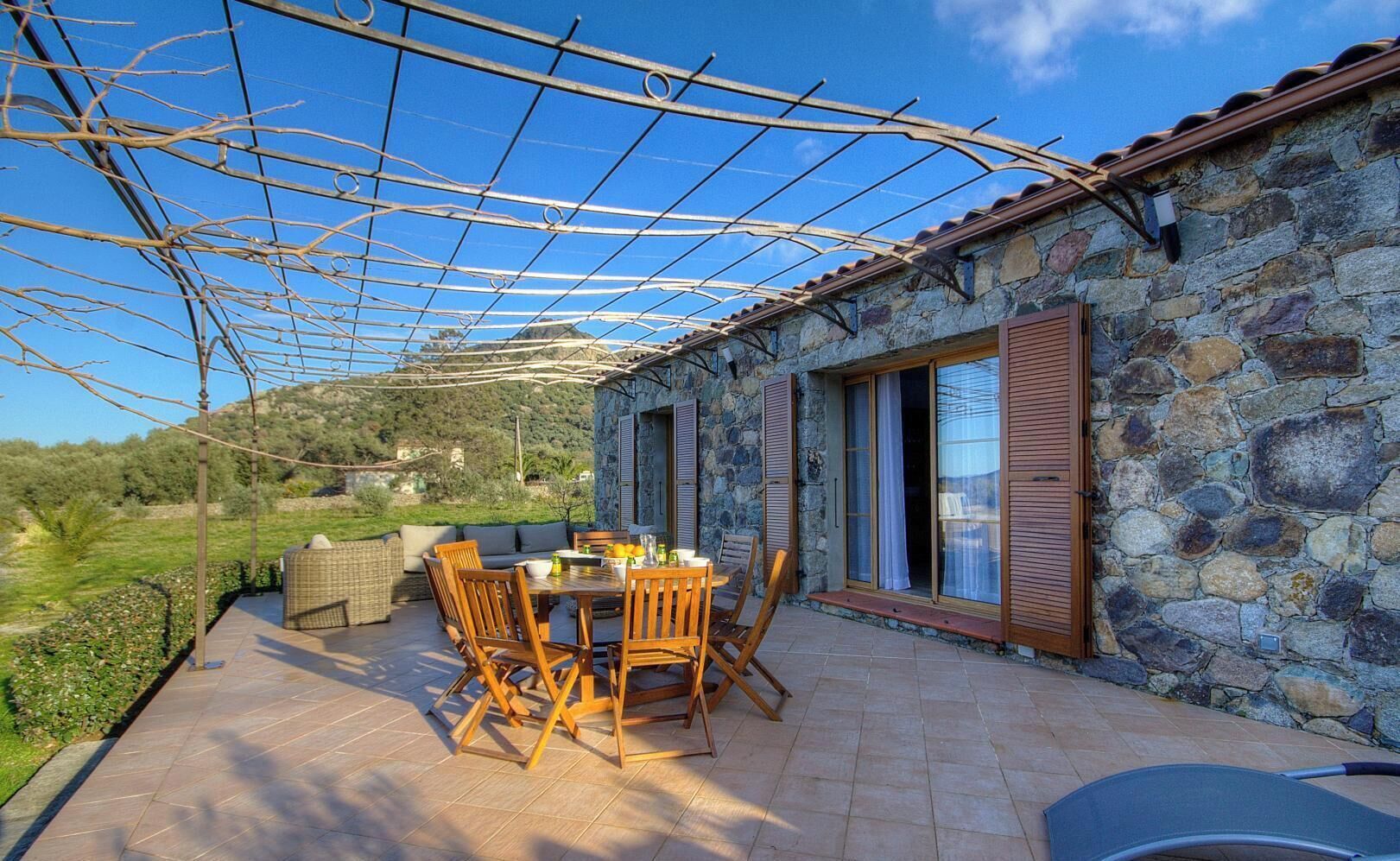 Un edificio in pietra con patio coperto, mobili da esterno e vista sulla campagna.