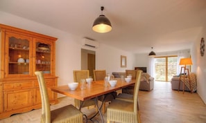 A dining area with a wooden table, wicker chairs, a cabinet with glassware, and a hanging light fixture. - Sheepfold - FELICETO - Vacation Rental (FELICETO)