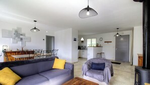 A modern living room with a sofa, armchair, and a dining area with a table and chairs. - The San Michele - SISCO (SISCO)