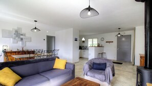 A modern living room with a sofa, armchair, and a dining area with a table and chairs. - The San Michele - SISCO (SISCO)