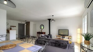 A living room with a sofa, a dining table with chairs, a TV, a lamp, and a window. - The San Michele - SISCO (SISCO)