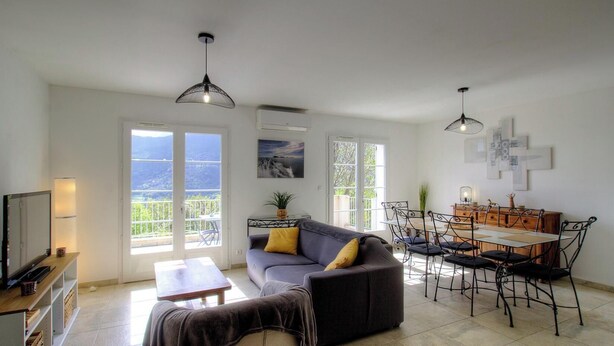 A spacious living area with a sofa, dining table, chairs, and a TV. - The San Michele - SISCO (SISCO)