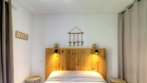 A bedroom with a wooden headboard, two bedside lamps, a bed with a patterned bedspread, and a wall-mounted decor piece above the bed. - The San Michele - SISCO (SISCO)