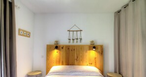 A bedroom with a wooden headboard, two bedside lamps, a bed with a patterned bedspread, and a wall-mounted decor piece above the bed. - The San Michele - SISCO (SISCO)