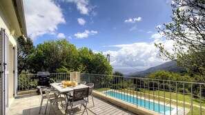 A balcony with a table and chairs, a barbecue grill, and a swimming pool with a view of mountains. - The San Michele - SISCO (SISCO)