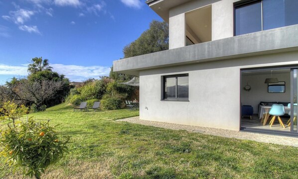 A modern two-story house with a patio area, outdoor seating, and a view of the surrounding landscape. - Le Clap - BASTELICACCIA (BASTELICACCIA)