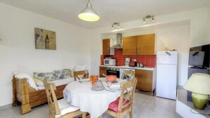 Un espacio habitable compacto con comedor, kitchenette y cama.