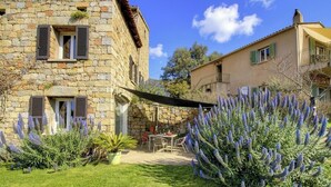 Un edificio de piedra con un patio, mobiliario exterior y plantas de lavanda.