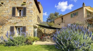 Ein Steinhaus mit Terrasse, Sitzgelegenheiten im Freien und Lavendelpflanzen.