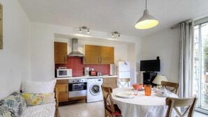 Una cocina compacta con lavadora, microondas y comedor con mesa y sillas.