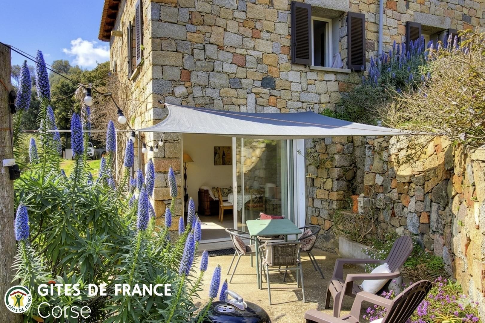 A stone building with a patio area, outdoor seating, and a covered table.