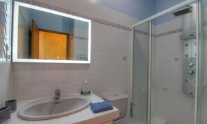 Ein Badezimmer mit Waschbecken, Spiegel, Toilette und Dusche.