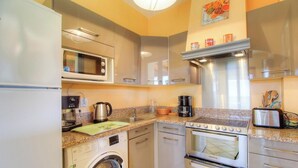 A compact kitchen with a microwave, coffee maker, toaster, oven, and washing machine. - Les oliviers 1 - SOLLACARO (SOLLACARO)