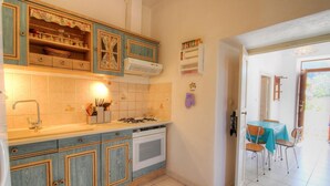 La cuisine est équipée d’une cuisinière à gaz, d’un four et de placards. On y trouve également un coin repas avec une table et des chaises.