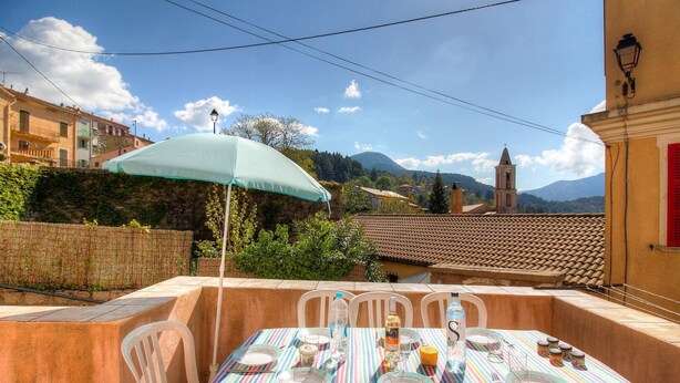 Un espace de restauration en plein air avec une nappe à rayures, des chaises et une table dressée pour un repas.
