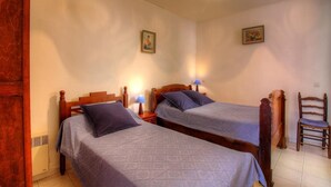 Une chambre avec deux lits en bois, chacun doté d’une tête de lit, d’une table de chevet, d’une lampe et d’une chaise.