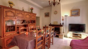 Un coin repas avec des meubles en bois, une cheminée, un téléviseur et une horloge au mur.