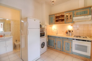 Una cocina con refrigerador, lavadora, horno, pileta y alacenas.