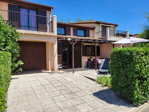 Ein zweigeschossiges Haus mit überdachter Terrasse, Garage und gepflegtem Garten.