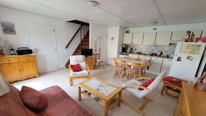 A compact living space with a sofa, chairs, a dining table, a kitchen area, and a staircase. - Nice holiday house, 3 bedrooms, AIRCO upstairs, a secured residence with pools,slides. Wifi, at... (PORTIRAGNES)