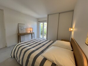 Ein Schlafzimmer mit Bett, Nachttischen, einem Schreibtisch und einem Fenster mit Blick.