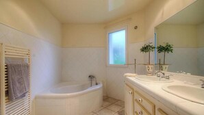Ein Badezimmer mit einer Badewanne, zwei Waschbecken, einem Fenster und einem Spiegel.