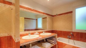 Ein Badezimmer mit zwei Waschbecken, einem großen Spiegel, einer Badewanne und einem Fenster.